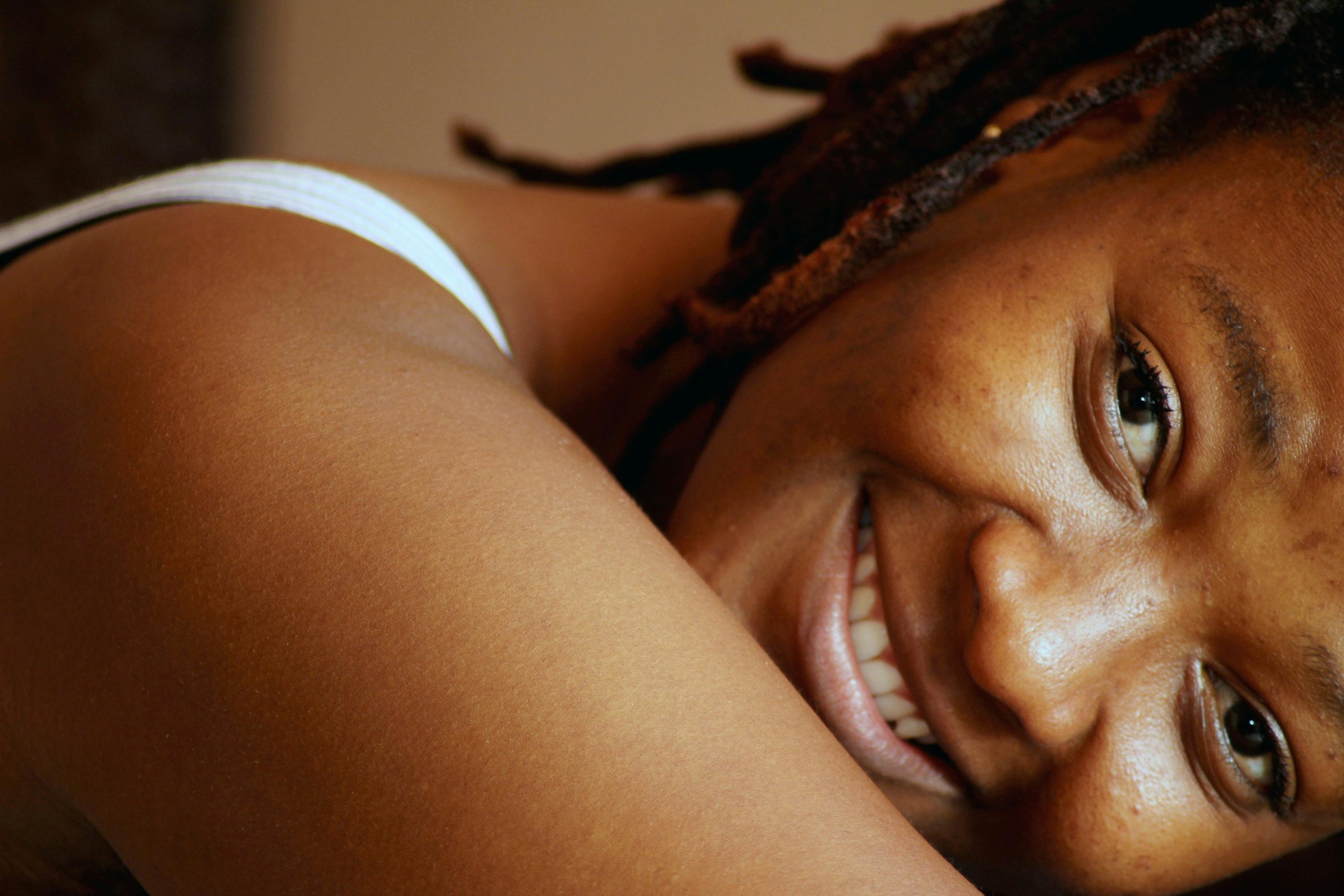 Close-up of a smiling black woman lounging indoors, emanating warmth and joy.